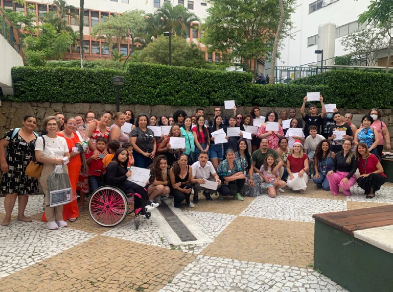 Grupo reunido ao ar livre com certificados, em registro do Programa Dona Carolina Tamandaré.